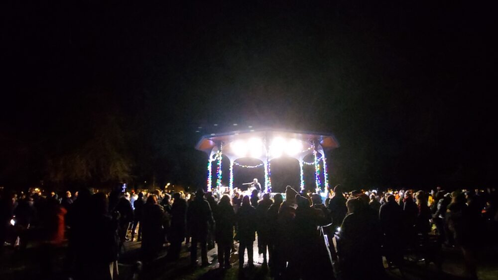 Grange pavilion bandstand with Christmas lights and a crowd of people