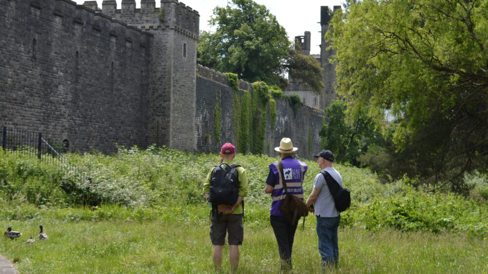 Photo of guided walk volunteer outside Cardiff castle in Bute Park.